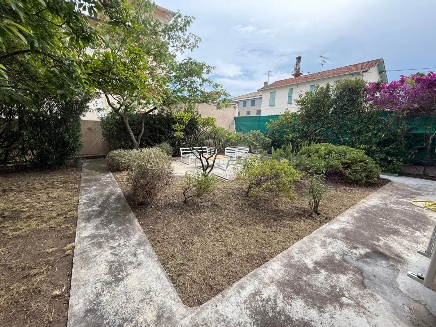 Le même jardin débroussaillé, arbustes taillés et allées dégagées jusqu'au salon de jardin, après travaux